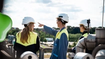 Group of people pointing in the distance on factory roof. 