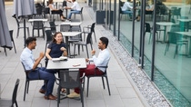 Three young employees sitting outside a  table and talking  animatedly.