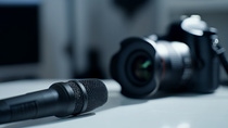 Studio microphone and blurry professional camera on a table  
