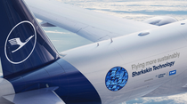 A Lufthansa plane in mid-flight high above the clouds. A sticker on its side says it is flying more sustainably with sharkskin technology (Photo: Lufthansa Cargo).