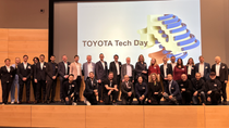 Group photo taken during Toyota Tech Day, featuring participants in front of a large presentation screen displaying the event title “TOYOTA Tech Day.” The setting is a modern conference hall with a wooden stage and a projected slide that includes a stylized graphic of automotive components. The image reflects a professional event focused on technology exchange and partnership in the automotive industry. Group photo taken during Toyota Tech Day, featuring participants in front of a large presentation screen displaying the event title “TOYOTA Tech Day.” The setting is a modern conference hall with a wooden stage and a projected slide that includes a stylized graphic of automotive components. The image reflects a professional event focused on technology exchange and partnership in the automotive industry.