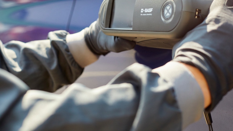 Painter holds a spectrophotometer on a blue car body. Painter holds a spectrophotometer on a blue car body.
