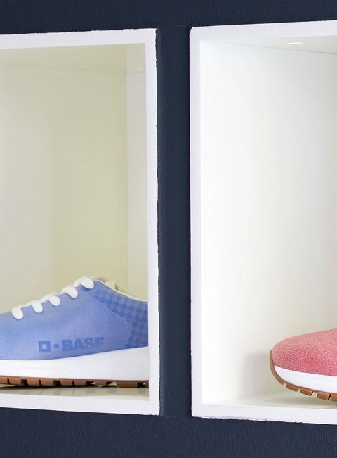 Four shoes with BASF logo  in four colors on a shelf.