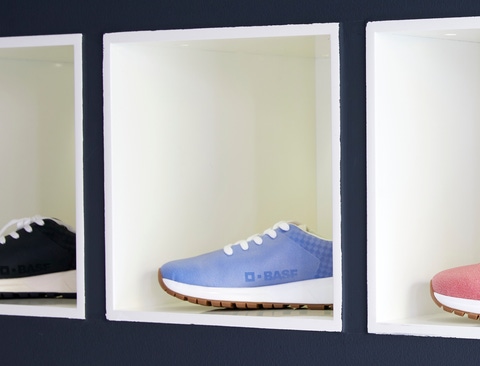 Four shoes with BASF logo in four colors on a shelf. Four shoes with BASF logo in four colors on a shelf.