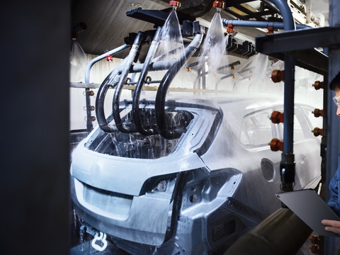 Car bodies being cleaned prior to spraying in car factory. Car bodies being cleaned prior to spraying in car factory.