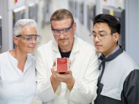 Three employees in different work clothes checking a painted panel 