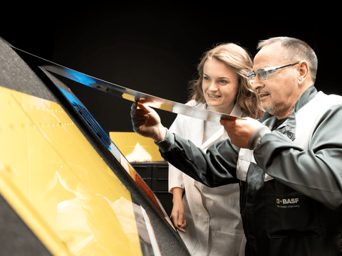 Zwei Mitarbeitende begutachten ein lackiertes Blech