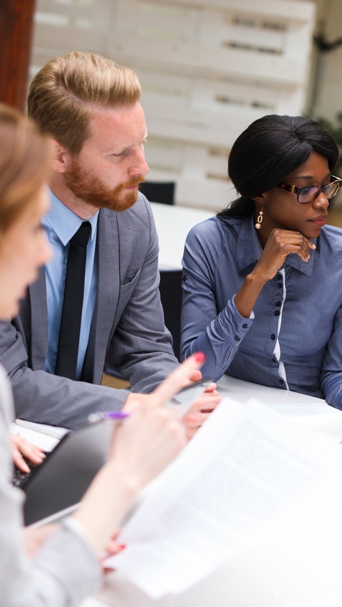 Group of business people is working on new business strategy with a financial analyst while analyzing financial chart during meeting in the office.