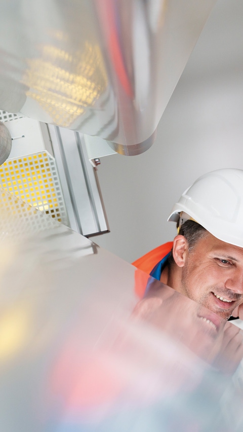 In a roll-to-roll process, functional films with a riblet structure are produced. The fine riblets are barely visible to the human eye. Applied to aircraft, they reduce dragon flow-relevant parts and thus save fuel. Marcel Schumacher shows project manager Dr. Sebastian Hartwig the manufacturing process of BASF's product NovaFlex SharkSkin, in the aviation industry known as shark skin technology.